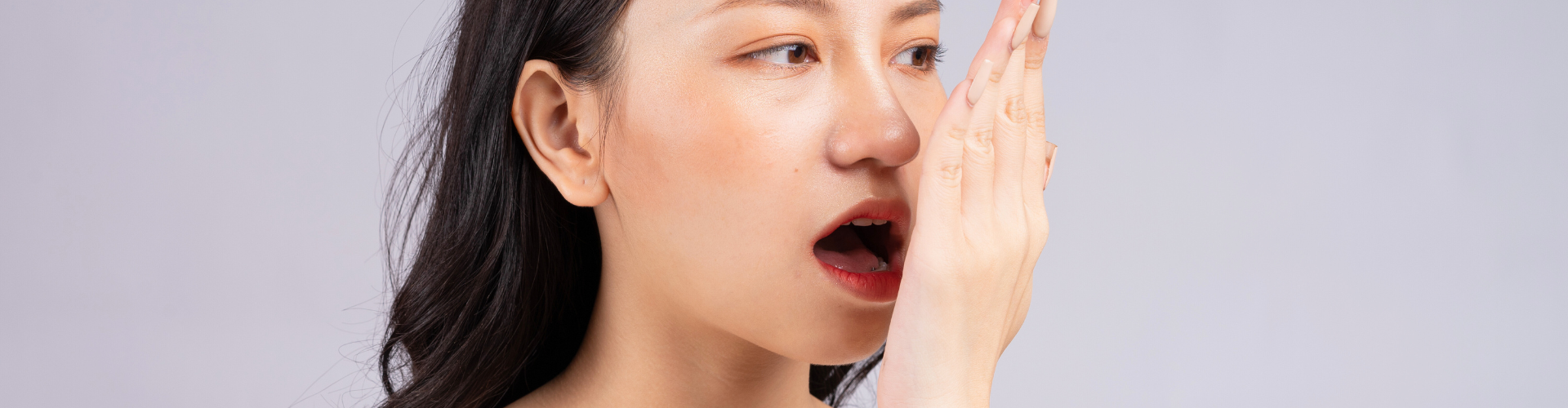 Woman blowing her breath into her hand.